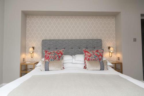 a bedroom with a large white bed with red pillows at Ultimate Coastal Luxury - 5 Bed, Spacious, Parking, Hot Tub in Malborough