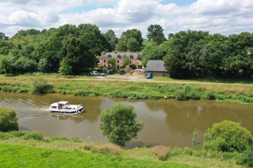 a boat in a river in front of a house at Maison au calme pour 7 personnes in La Chapelle-de-Brain