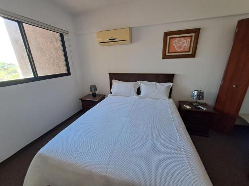 a bedroom with a large white bed with two windows at Precioso Depa 3 dormitorios en La Casona in Santa Cruz de la Sierra