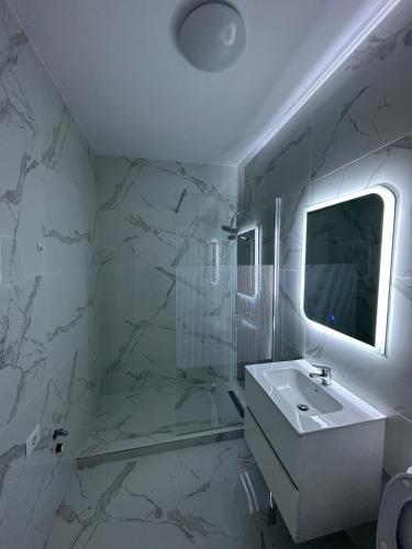 une salle de bain blanche avec un lavabo et un miroir dans l'établissement Affordable Cute & Comfy Flat, à Dobroeşti