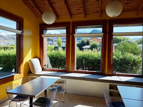 a room with a table and chairs and windows at Kau Si Aike in El Chalten