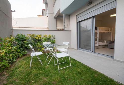 a patio with two chairs and a table on the grass at Elymara Family Vacation Home in Nikiti
