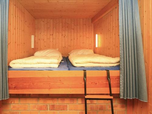two beds in a wooden cabin with a chair in it at Bootshaus, Mirow in Mirow