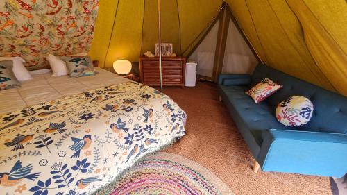 - une chambre avec une tente dotée d'un lit et d'un canapé dans l'établissement Le monde d'Echozellia - Tente M, à Saint-Germain-des-Champs