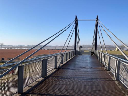 a bridge over a field with a blue sky at Riverside Retreat with Comfort in Geesthacht