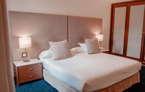 a bedroom with a large white bed with two lamps at Gran Hotel Soller in Sóller