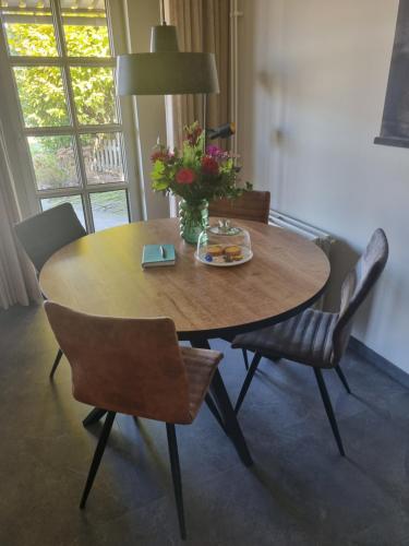 a wooden table with chairs and a vase of flowers at Hemmer Hofstede in Hem