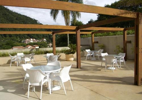 un patio con sedie e tavoli bianchi e un pergolato in legno di resort comfort ad Araras Petropolis