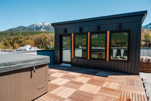 a black tiny house with a deck with a view at Downtown Loft with Rooftop Hot Tub by StayIn in Fernie