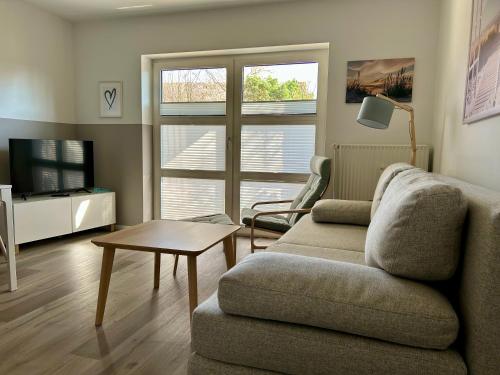 Una sala de estar con un sofá, una mesa y un televisor. en Ferienwohnung Bullerby-Büsum, ehemals Holländerei, en Büsum