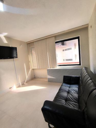 a living room with a black couch and a window at Central Paradise 1 room 2 o 3 pax in Porlamar