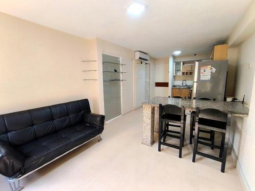 a living room with a black leather couch and a kitchen at Central Paradise 1 room 2 o 3 pax in Porlamar