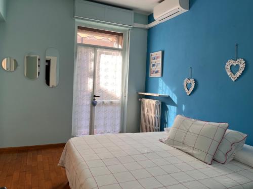a blue bedroom with a bed and a window at Casa Piemont in Casale Monferrato