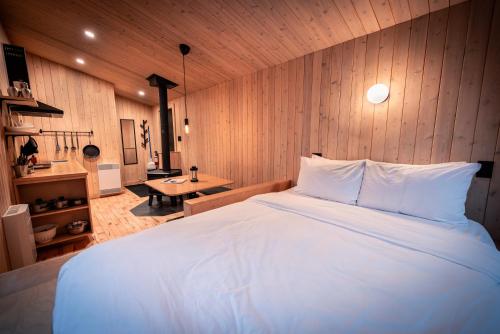 a bedroom with a large white bed and a table at ÈST Éco-cabines in Nouvelle