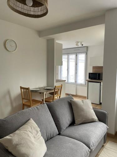 a living room with a gray couch and a table at Charmant studio dans le quartier historique in Châteauroux