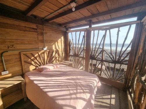 a bed in a room with a view of the ocean at Las delicias del paraiso in El Palo Verde