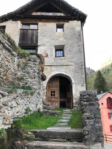 an old stone building with a wooden door and stairs at Bijou aus dem 18 Jahrhundert im Maggiatal in Fusio