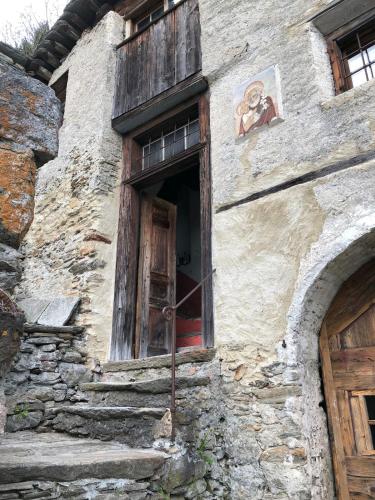 an old building with a door and a painting on the side at Bijou aus dem 18 Jahrhundert im Maggiatal in Fusio