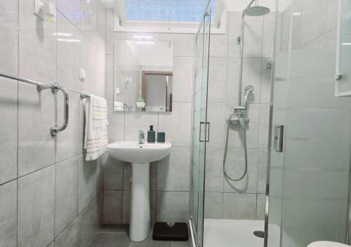 リベイラ・ブラーヴァにあるBanana Loversの洗面台とシャワー付きの白いバスルーム