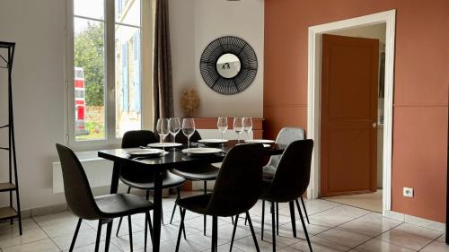 une salle à manger avec une table, des chaises et un miroir dans l'établissement La maison de la Loire, à Nevers