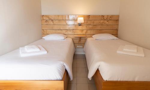 two beds in a small room with white sheets at Casa da Praya in Horta