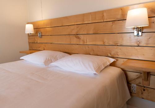 una cama con cabecero de madera y dos almohadas en Casa da Praya, en Horta