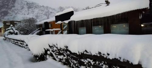 a snow covered house with a row of snow covered bushes at Kau Si Aike in El Chalten