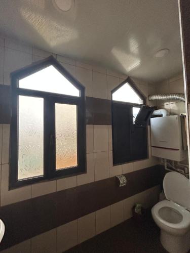 a bathroom with two windows and a toilet at Ideal apartments for family in Ganja