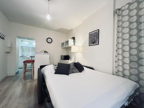 une chambre avec un grand lit blanc et une cuisine dans l'établissement Duruy D studio confort proche piscine et patinoire, à Reims