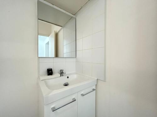 une salle de bain blanche avec un lavabo et un miroir dans l'établissement Duruy D studio confort proche piscine et patinoire, à Reims