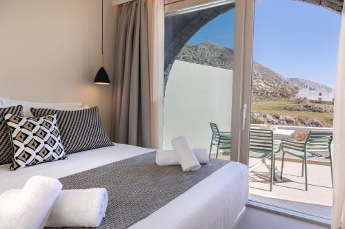 a bedroom with a bed and a balcony with a view at Depalyma Suites in Emporio Santorini