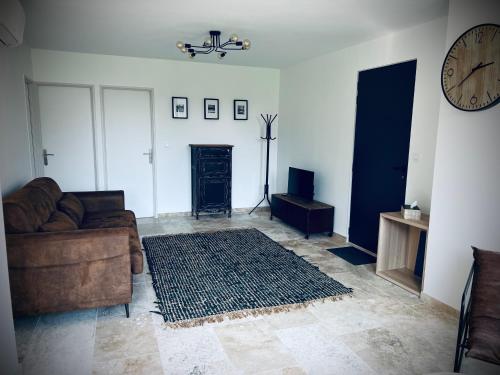 un salon avec un canapé et une horloge au mur dans l'établissement L Orangerie, à Maubec