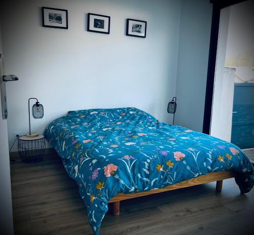 - un lit avec une couverture bleue et des fleurs dans l'établissement L Orangerie, à Maubec