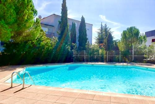 une grande piscine bleue avec des arbres et un bâtiment dans l'établissement Détente absolue suite luxueuse avec balnéo et PS5, à Saint-Vincent-de-Barbeyrargues
