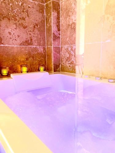 une baignoire remplie d'eau bleue dans une salle de bain dans l'établissement Détente absolue suite luxueuse avec balnéo et PS5, à Saint-Vincent-de-Barbeyrargues