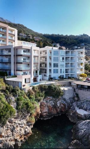 an apartment building on a cliff next to the water at Paradise beachfront view 2 in Dobra Voda