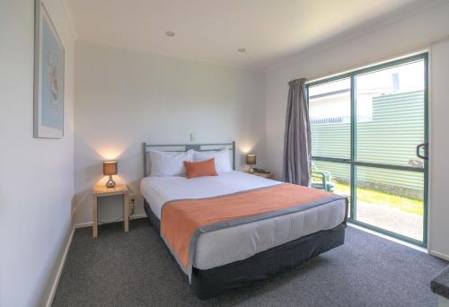 a bedroom with a bed and a large window at Camelot Motor Lodge and Conference Centre in Palmerston North