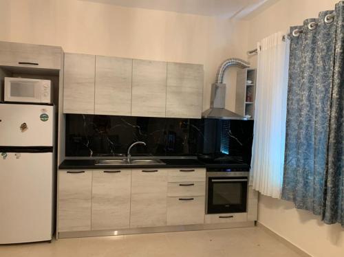 une cuisine avec des armoires blanches et un réfrigérateur dans l'établissement Double room with shared bathroom, à Tirana