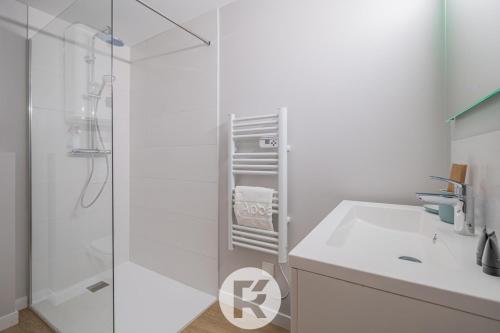 une salle de bain blanche avec un lavabo et une douche dans l'établissement R'Apparts Latelier D'exception S2, à Grenoble