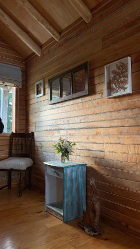 a room with a wooden wall with a table and a chair at Lodge El Sarao A Una Hora De Puerto Varas in Fresia