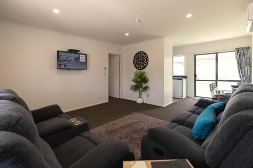 a living room with two couches and a tv at Camelot Motor Lodge and Conference Centre in Palmerston North