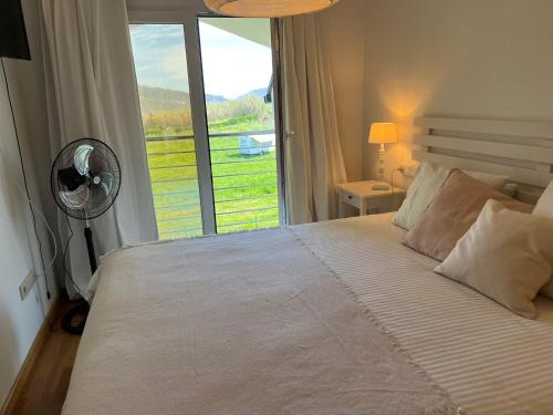 una camera con letto, ventilatore e finestra di Apartamentos Galicia Norte a O Porto de Espasante