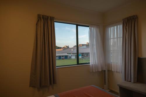a bedroom with a window with a view of a house at Camelot Motor Lodge and Conference Centre in Palmerston North