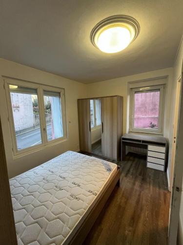 une chambre avec un lit, une table et des fenêtres dans l'établissement Au relais de la gare, à Quimper