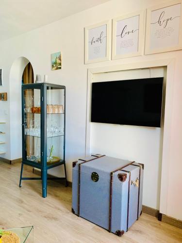 a living room with a tv and a blue cabinet at Private apartment with stunning ocean views and sunset. in Taurito
