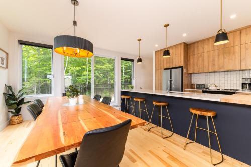 a kitchen with a large wooden table and chairs at Chalets Grande-Pointe au Massif de Charlevoix -Vélos - Rando -ski-in ski-out in Petite-Rivière-Saint-François