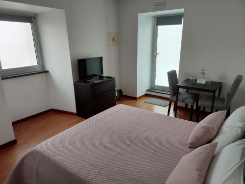 a bedroom with a bed and a television and a table at Retiro das Camélias 2 in Lajes das Flores