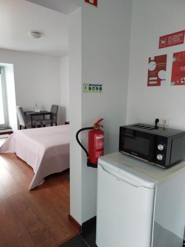 a room with a bed and a microwave on a counter at Retiro das Camélias 2 in Lajes das Flores