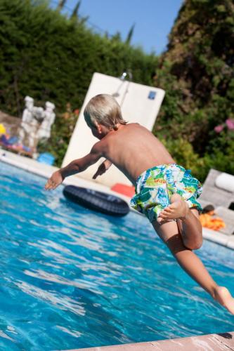 un jeune garçon sautant dans une piscine dans l'établissement Saint Paul le Marseillais Tentes Equippees Hébergements Insolites Lodges, à Mèze