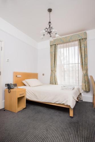 a bedroom with a bed and a dresser and a window at Rewley House University of Oxford in Oxford